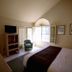 4 Seasons at Desert Breezes Palm Desert guest room with bay window, armchair, TV and bed