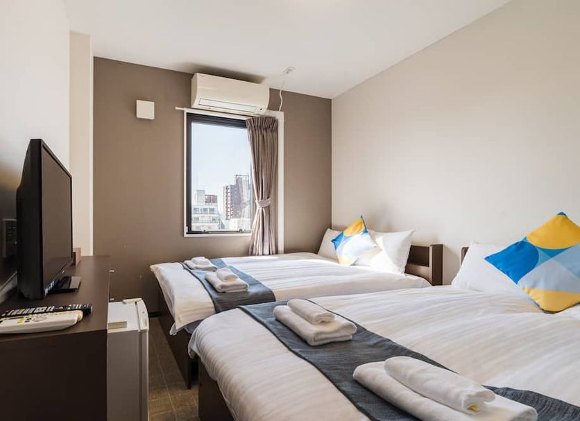 Okini - Doyanen Hotels in Osaka guest room with two twin beds and a city-view window