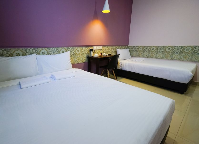Grand Fc Hotel in George Town room with one double bed and one single bed beside a small desk