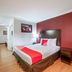 OYO Hotel Mcallen Airport South guest room with bed, red accent wall, desk and lamp in McAllen