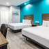 Scottish Inns & Suites - Kingwood in Humble room with two beds and teal accent wall