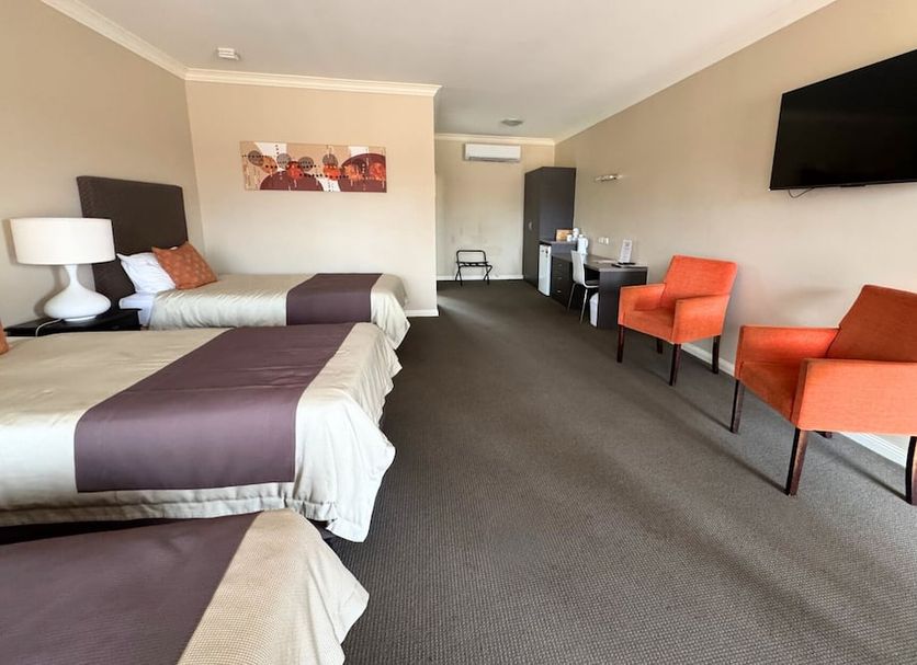 Sundowner Motel Hotel in Whyalla Norrie: spacious guest room with two beds, seating area and wall-mounted TV