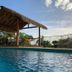 Island Views Airlie Beach pool with thatched cabana, lounge chairs and ocean-view sky at sunset