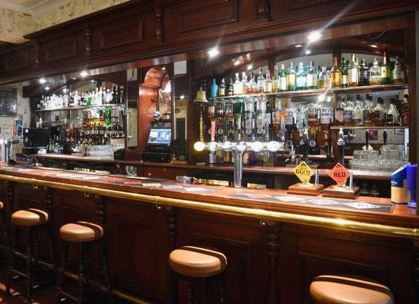 Tongadale Hotel in Portree bar with wooden counter, stools, and stocked backbar