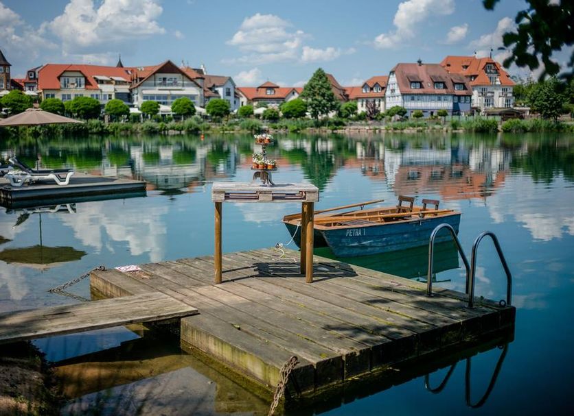 Seehotel Niedernberg - Das Dorf am See lakeside dock and boats with village reflection in Niedernberg