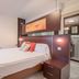 Hotel Vivar in Griñón bedroom with double bed, lounge chair and modern wood-paneled headboard