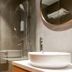 Caritas Oswald Cheung International House bathroom with glass shower, vessel sink, towel rack and round mirror in Hong Kong