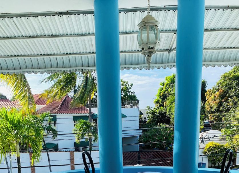 Villa Antonia 16 in Sosúa: balcony with table and chairs overlooking a pool and tropical trees