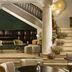 NH Madrid Nacional lounge with staircase, columns, seating area and green shelving in Madrid