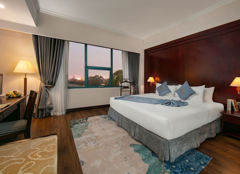 The Tray Hotel Hai Phong in Haiphong guest room with king bed, wood-paneled wall, and city view window
