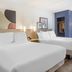 Spark by Hilton Atlanta Airport South College Park guest room with two beds, blue accent wall, and floor lamp