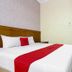 RedDoorz @ Seturan Raya 2 in Depok bedroom with white bed, red runner, and wooden wardrobe
