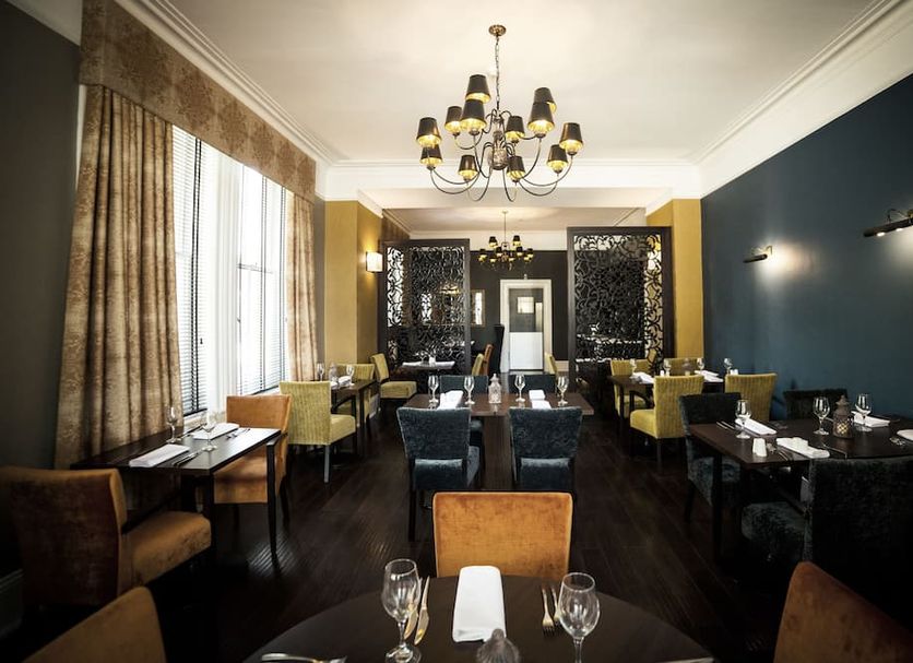 Steventon House Hotel in Abingdon dining room with chandeliers, dark walls and set tables