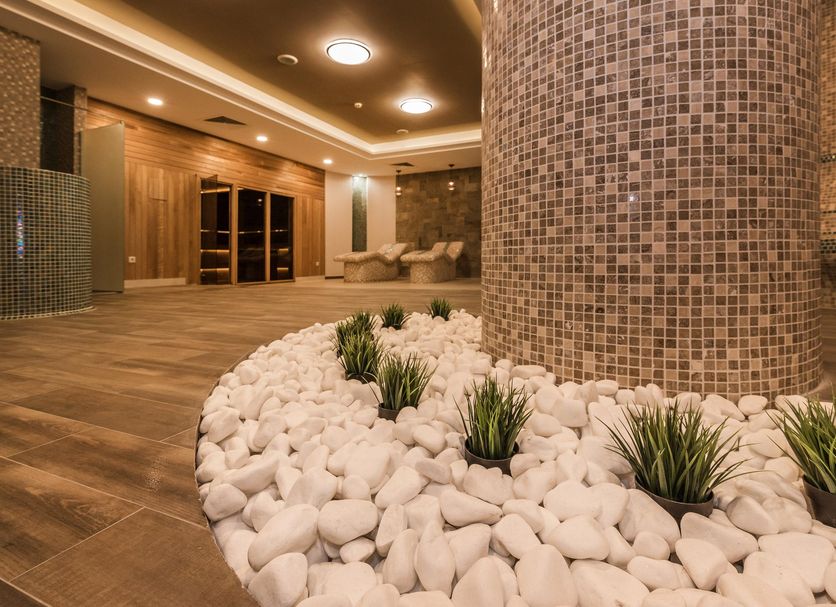 Lion Bansko Hotel in Bansko lobby with mosaic column, white stone planter, and warm ambient lighting