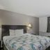 Motel 6 Wichita East room with queen bed, lamps, window, and patterned bedding in Wichita