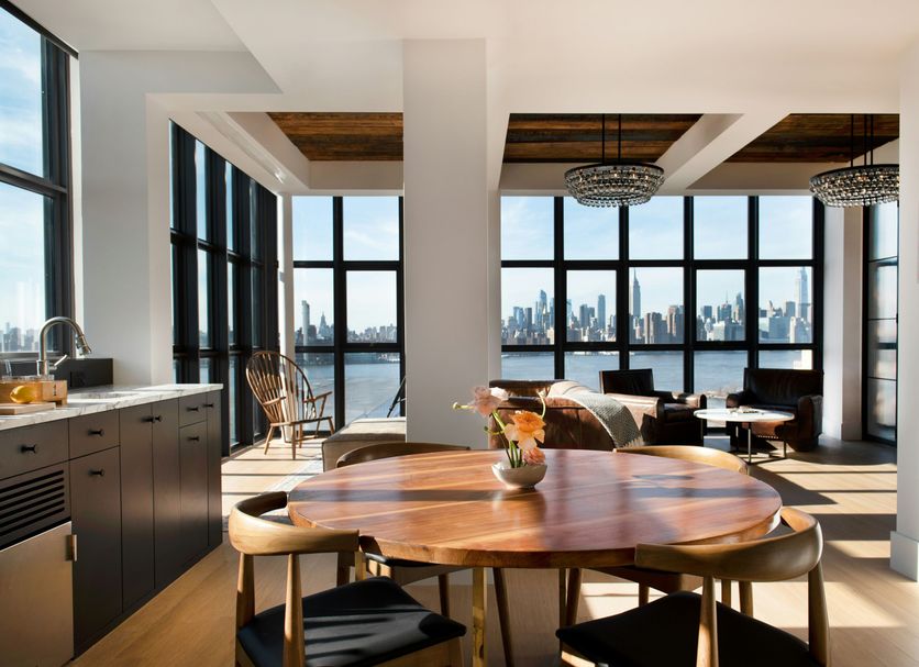 Wythe Hotel in Brooklyn with a bright loft-style lounge, round table, and skyline-view windows.