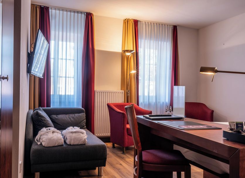 Hotel Osterkrug in Husum guest room with desk, armchair, sofa and large windows