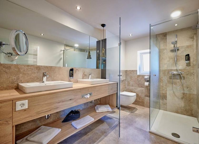 Landhotel Moorhof in Neuschönau bathroom with double sink vanity, toilet and glass shower