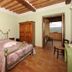 Agriturismo Poggio Tobruk in Pienza, rustic bedroom with wrought-iron bed and countryside view through doorway