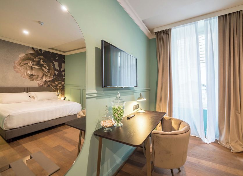 Palazzo 42 - Boutique Hotel & Suites in Pistoia, bedroom with bed, wall TV and small desk by balcony doors