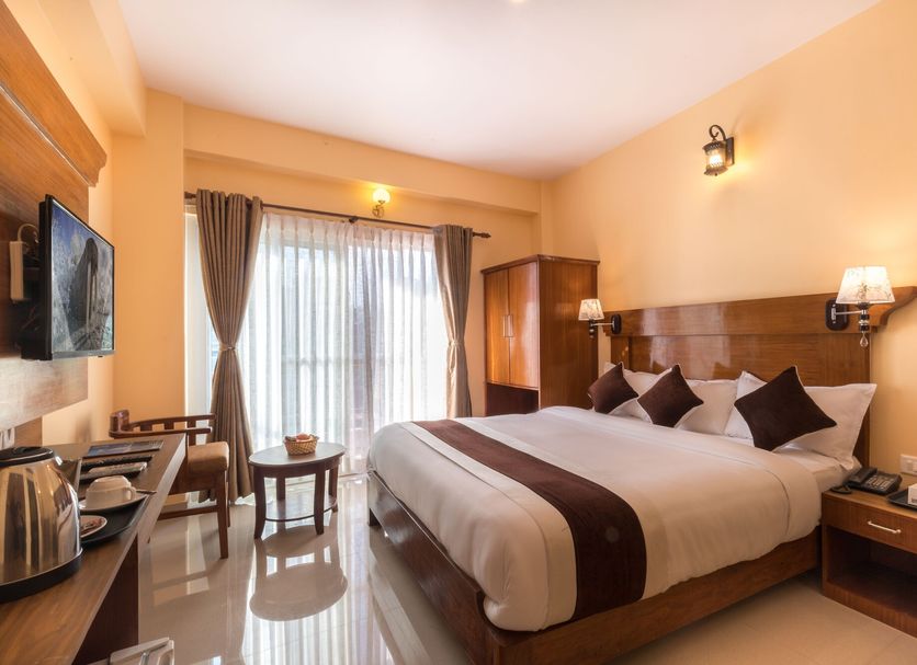 Hotel Lake Shore in Pokhara guest room with king bed, TV, desk and balcony doors