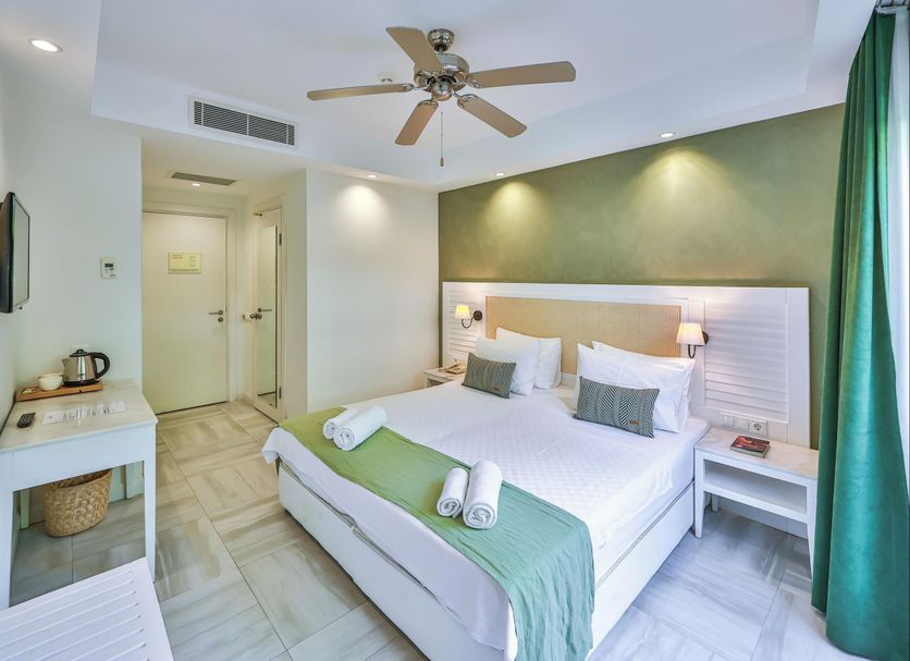 Livia Hotel, Kaş: bright double room with twin beds, ceiling fan, and green curtains