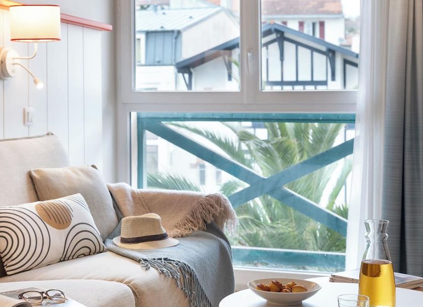 Résidence Pierre & Vacances Premium Haguna room with sofa, window seat, and sea-view palm trees in Biarritz