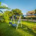 Hotel Royal Nest Entebbe garden swing set with hotel building and trees in the background
