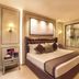 Grand Residency Hotel & Serviced Apartments in Mumbai: a modern bedroom with a bed, wall art, and glass shower