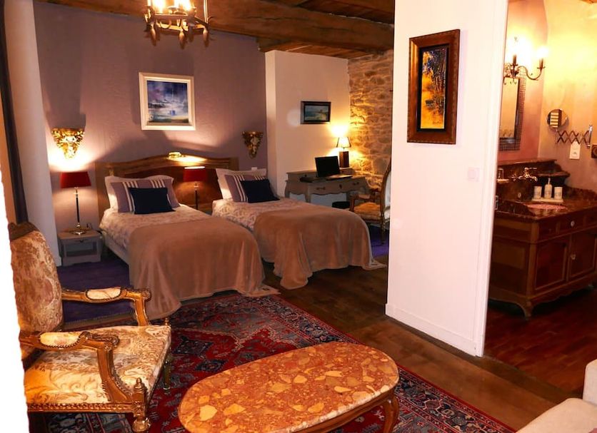 Manoir Desnachez, Ploërmel: rustic hotel room with twin beds, stone wall, seating area and bathroom doorway