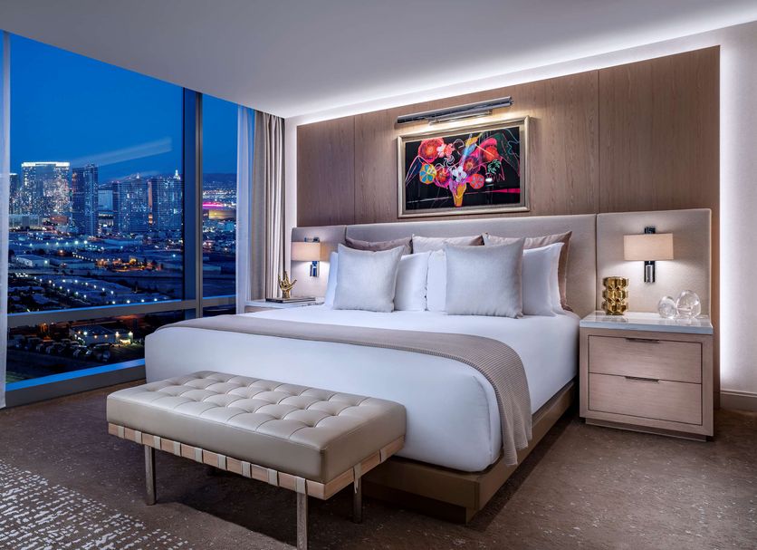 Palms Casino Resort Las Vegas guest room with city skyline view, king bed and bench by floor-to-ceiling window
