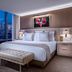 Palms Casino Resort Las Vegas guest room with city skyline view, king bed and bench by floor-to-ceiling window