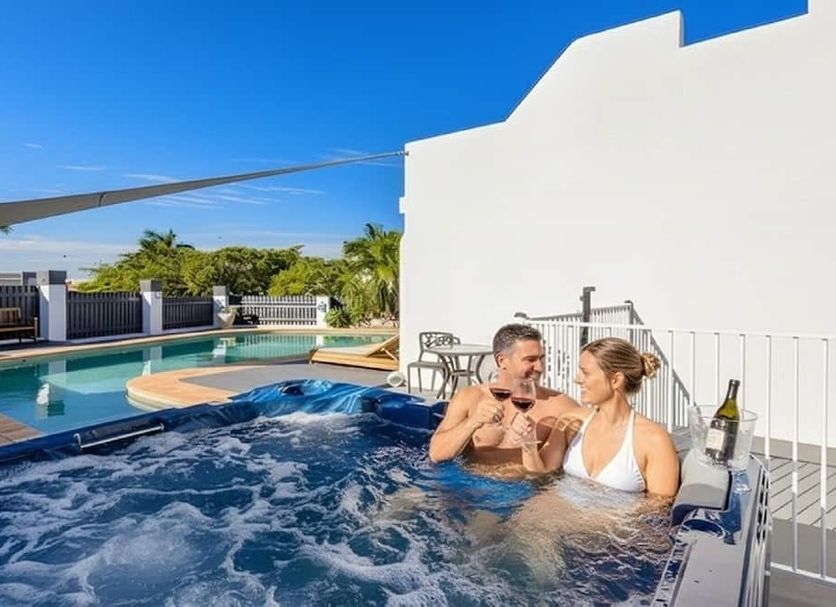 Aaron Motel in Gladstone with guests in an outdoor spa beside the pool under a blue sky