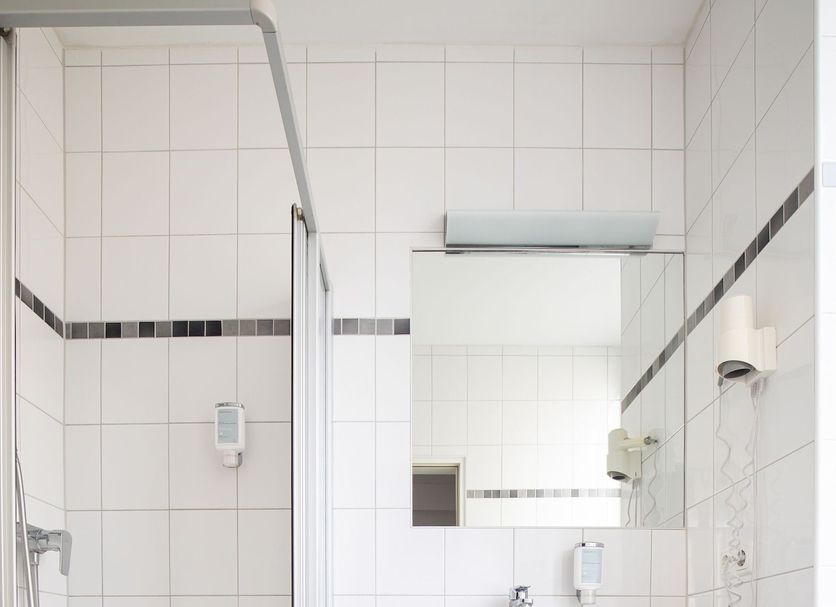 Hotel am Ludwigsplatz Gießen bathroom with shower, sink, mirror and tiled walls