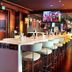 Hues Boutique Hotel Dubai bar lounge with long counter, high stools, and TV screens