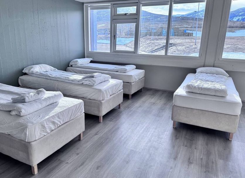 Hunavellir Guesthouse in Blonduos: simple guest room with four single beds and large mountain-view windows