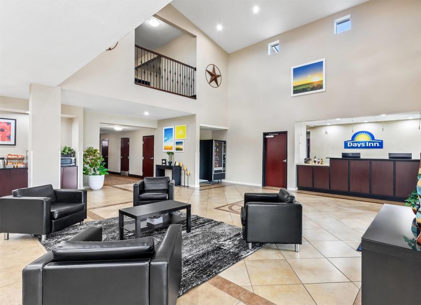 Days Inn by Wyndham Rockdale Texas lobby with black chairs, front desk, high ceiling and upper balcony