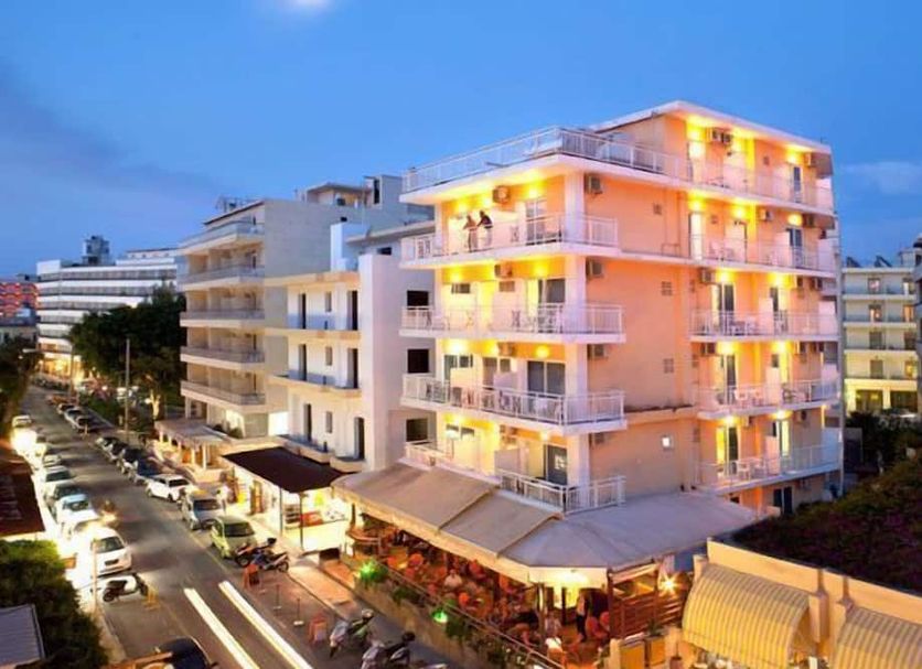 Pearl Hotel in Rhodes, lit beachfront-style hotel building on a lively street at dusk