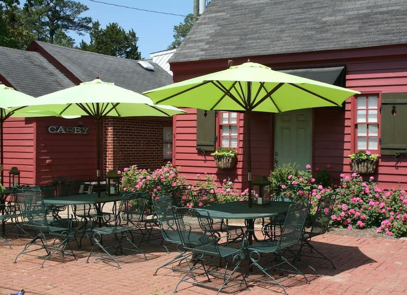 Williamsburg Manor B&B in Williamsburg patio with green umbrellas, tables, chairs, and pink flowers