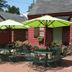 Williamsburg Manor B&B in Williamsburg patio with green umbrellas, tables, chairs, and pink flowers