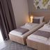 Forest Village Resort in Medjugorje guest room with two single beds, bedside lights and balcony curtains