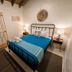 Waterside Inn, Vieques guest room with metal bed, blue bedding, nightstands, and open shelving