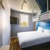ibis budget Lyon Villeurbanne room with bunk bed, white bed, wall-mounted TV and window in Villeurbanne
