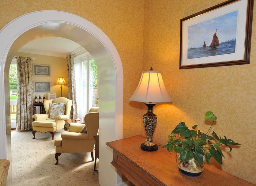 Marton Grange Country House in Bridlington: elegant lounge with archway, armchairs, lamp and framed sailboat art
