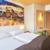 B&B Hotel Frankfurt City-Ost room with twin beds, wall art, and compact seating area in Frankfurt am Main