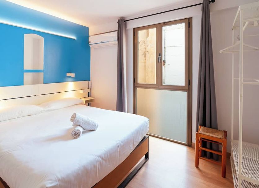 Forum Tarragona hotel room with double bed, blue accent wall, balcony door and window in Tarragona