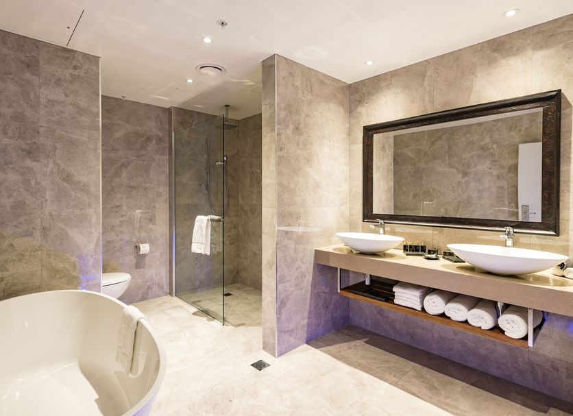 Distinction Christchurch Hotel bathroom with freestanding tub, double sinks, glass shower and toilet in Christchurch