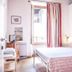 Alla Torre Del Barbarossa B&b Foresteria room with wrought-iron bed, striped curtains, and open window in Mandello del Lario