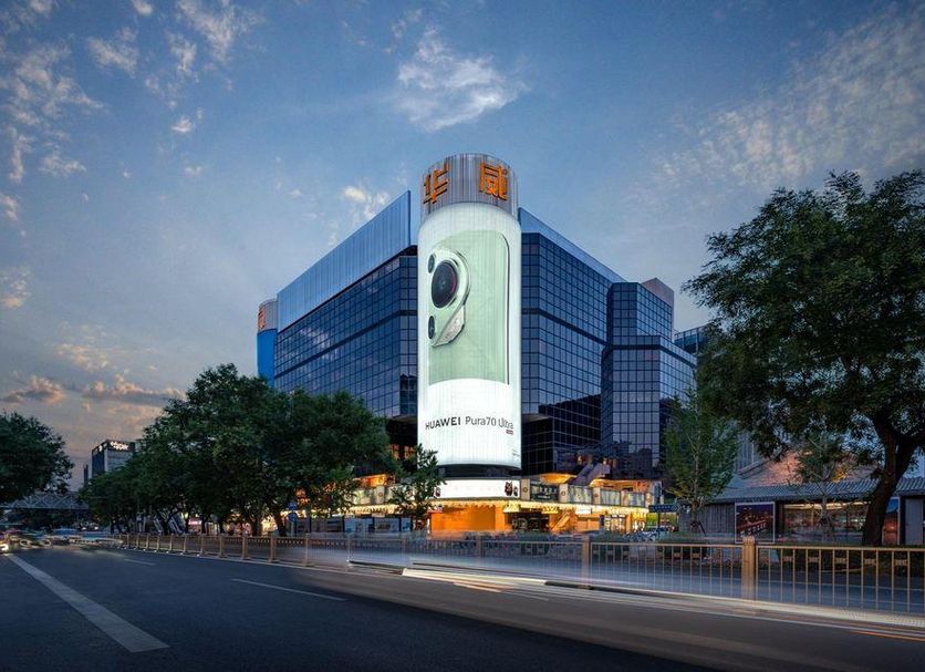Beijing Hwa Apartment Hotel in Beijing exterior at dusk with glass facade and city street view
