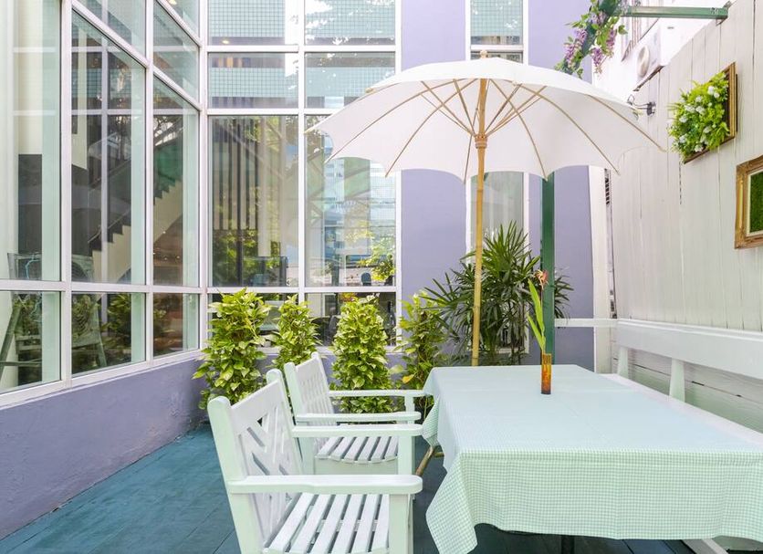 Pinnacle Lumpinee Park Hotel in Bangkok patio with white table, chairs and umbrella beside tall windows